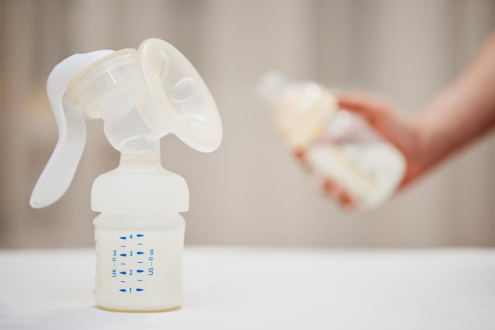 Silicone milk catcher, manual breast pump and wearable electric breast pump on a light surface